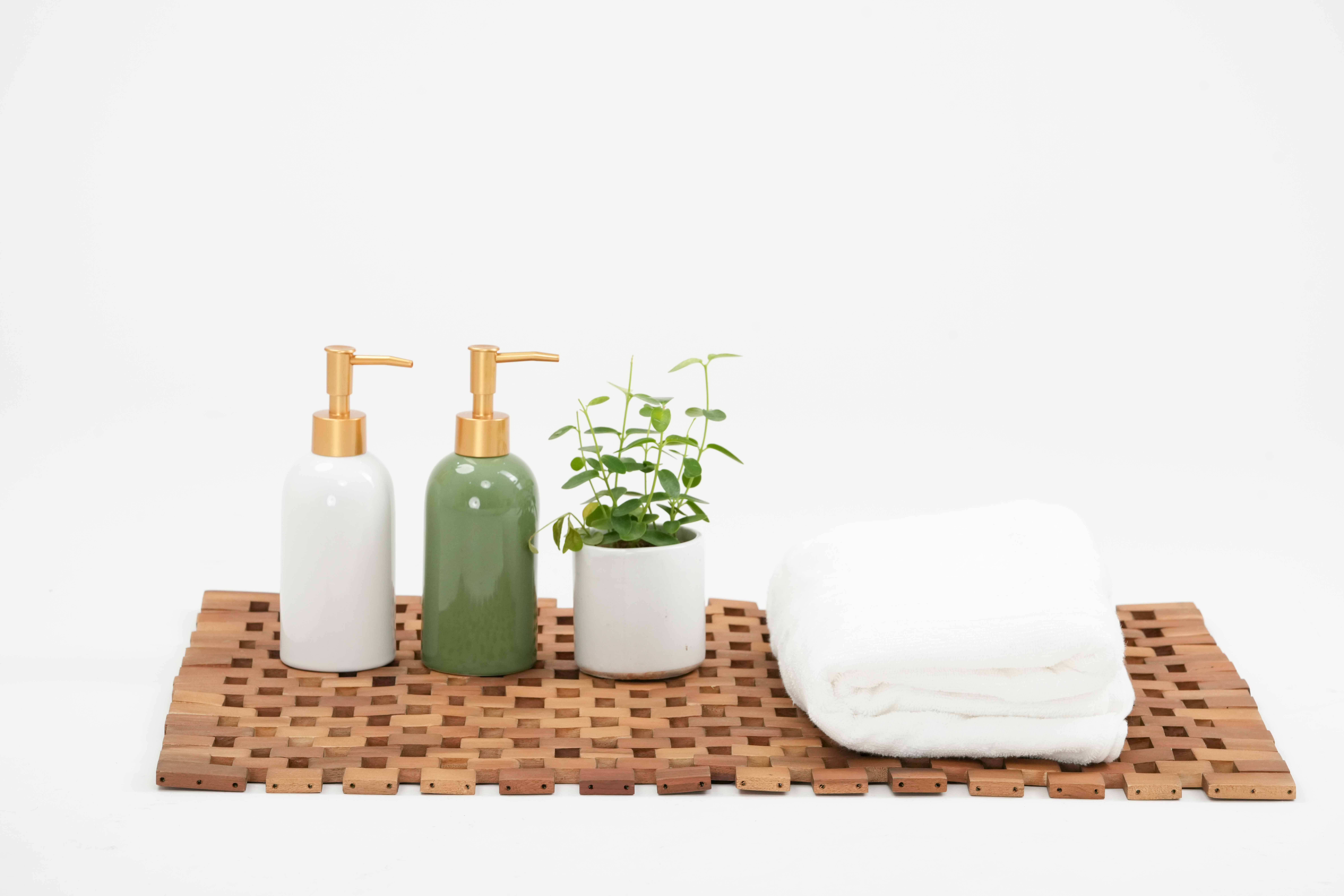 Acacia bath mat styled with dispensers, plant and towel