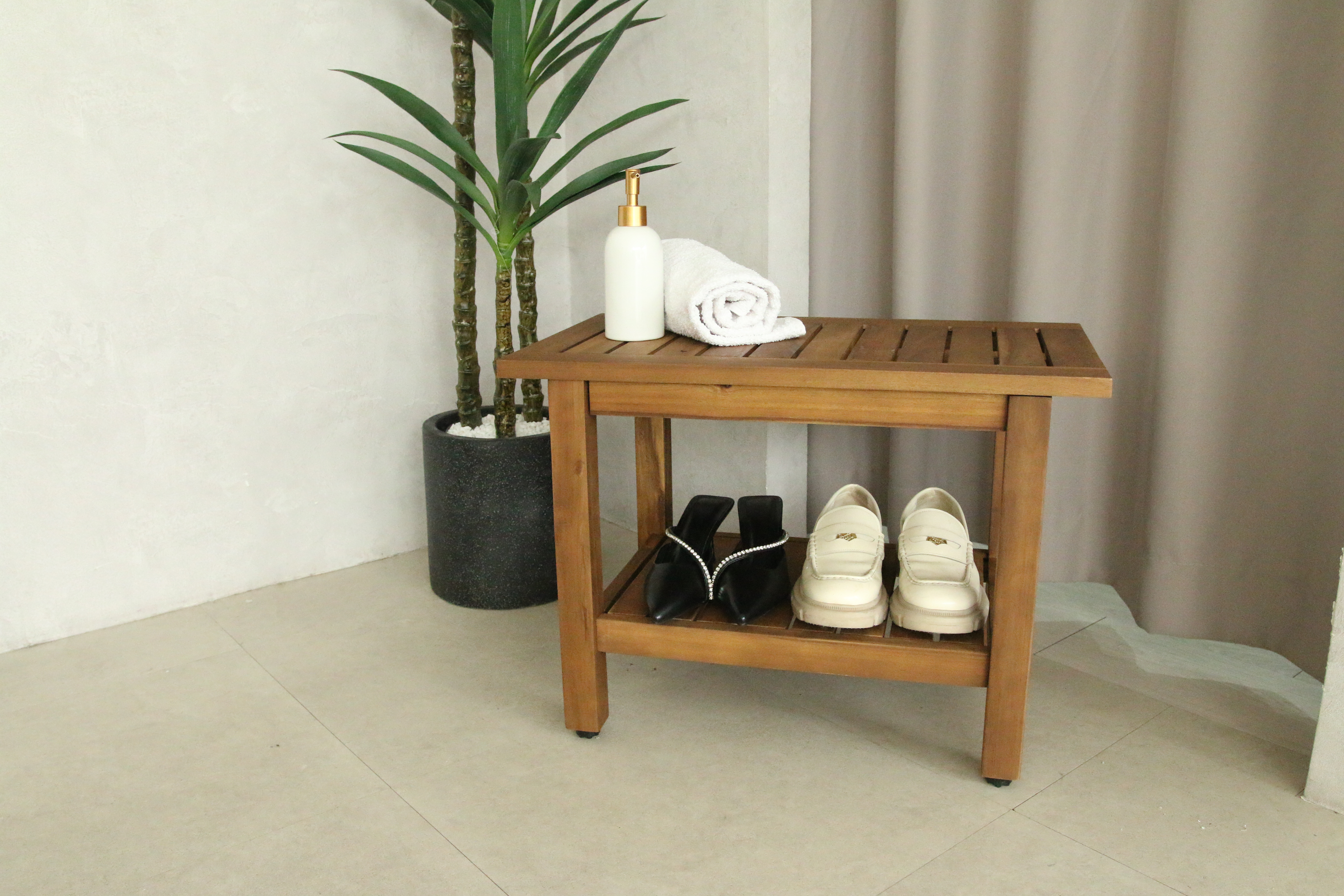 Acacia wood shower bench styled in an entryway with shoes and plant