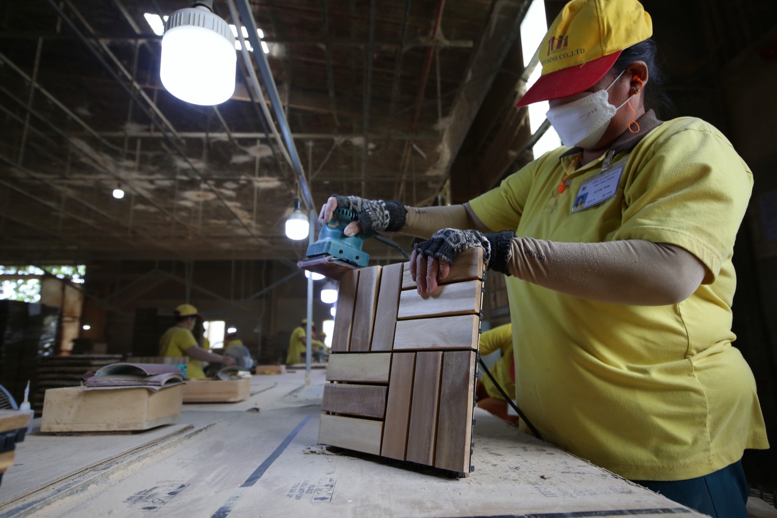 Craftworker hand-sanding an acacia deck tile in the factory